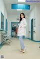 A woman in a white lab coat standing in a hospital hallway.