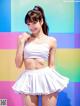A woman in a white top and a white skirt posing for a picture.