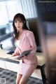 A woman in a pink suit sitting at a desk.