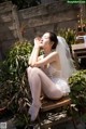 A woman in a wedding dress sitting on a wooden bench.