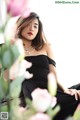 A woman in a black dress sitting next to a bunch of flowers.