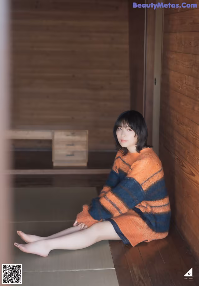 A woman sitting on the floor in a room.