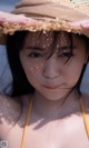 A woman wearing a straw hat on the beach.