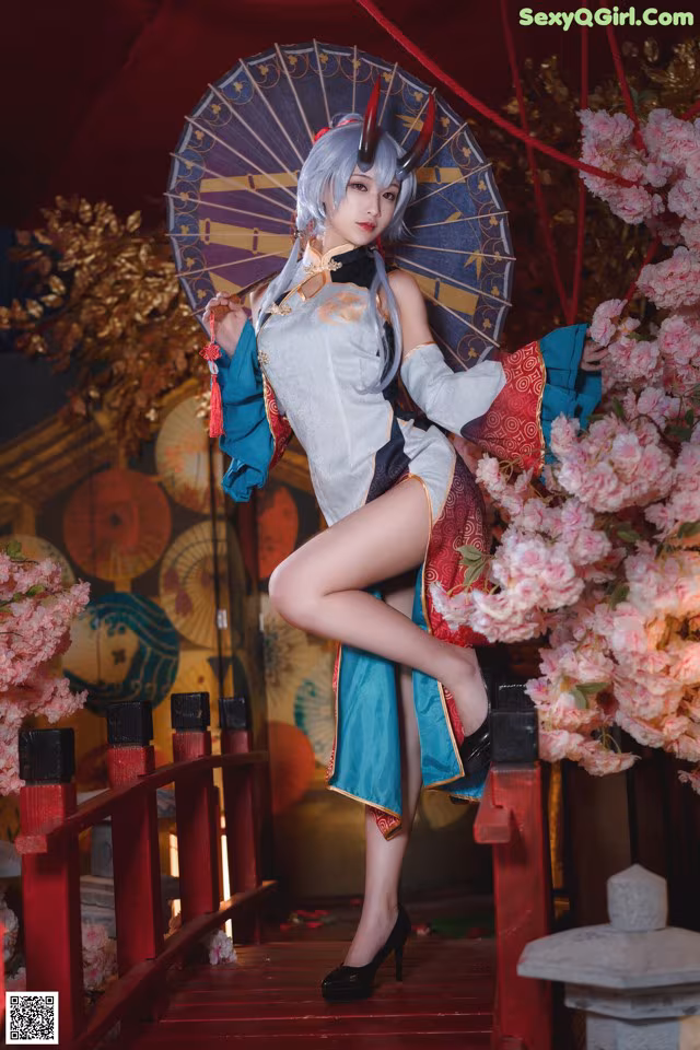 A woman in a blue and red outfit holding an umbrella.
