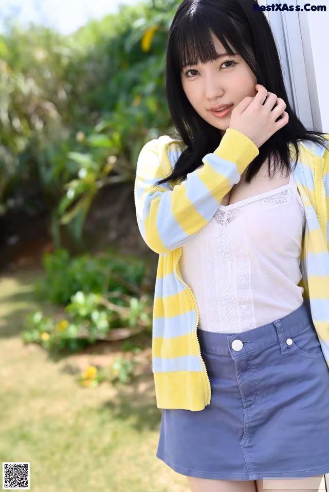 A young woman leaning against a wall with her hand on her chin.
