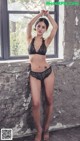 A woman in a black lingerie leaning against a window.