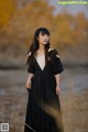 A woman in a black dress standing in a field.