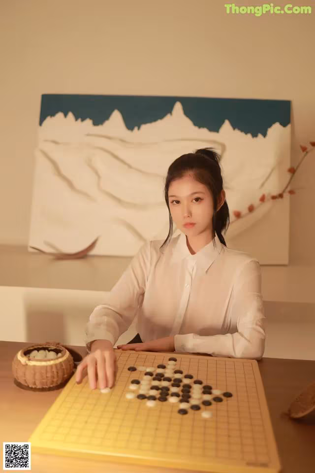 A woman sitting at a table playing a game of checkers.