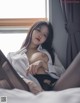 A woman sitting on top of a bed next to a window.