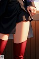 A woman in a black skirt and red knee high boots.