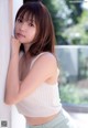 A young woman leaning against a wall with her hand on her chin.