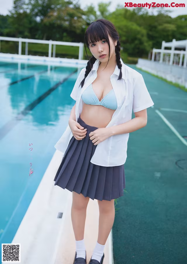 A woman in a school uniform standing next to a swimming pool.