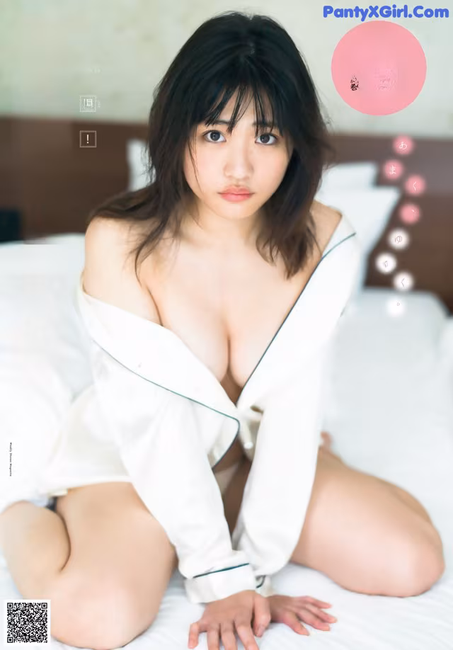 A woman in a white shirt is sitting on a bed.