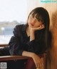 A woman leaning against a wooden wall with her hand on her chin.