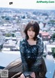 A woman sitting on top of a building next to a window.