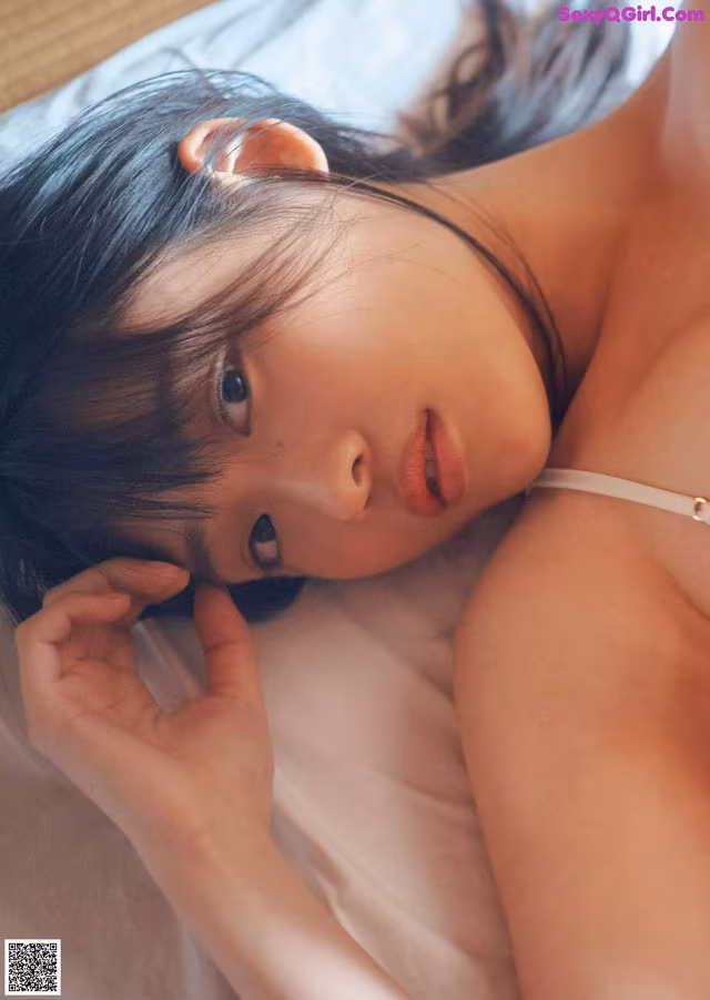 A woman laying on top of a bed next to a pillow.