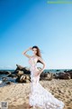 A woman in a white dress standing on a beach.