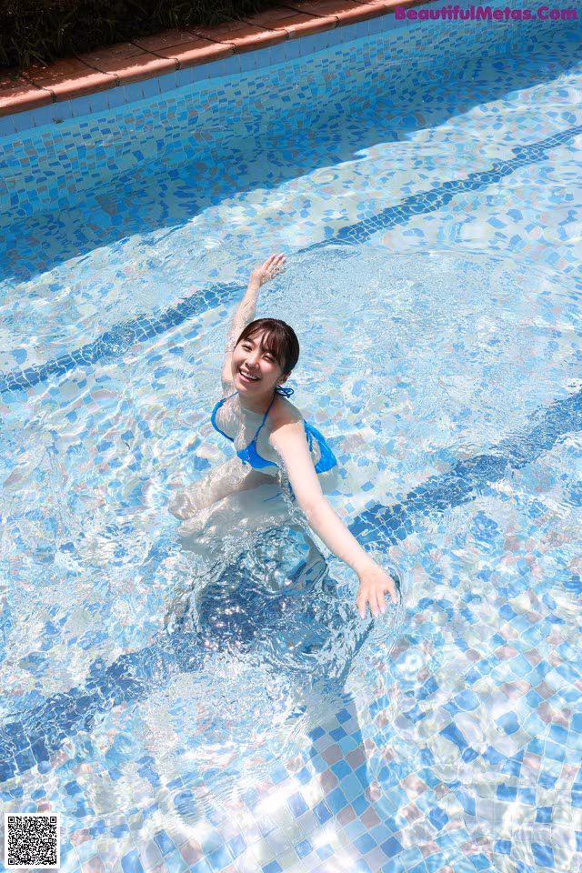 A woman in a blue bikini is swimming in a pool.