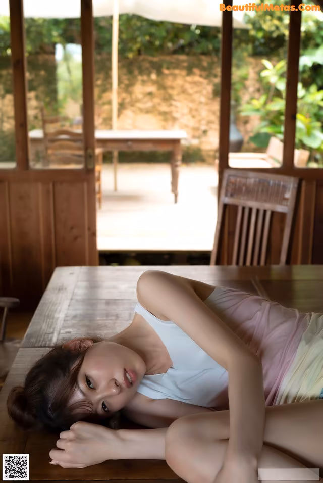 A woman laying on top of a wooden table.